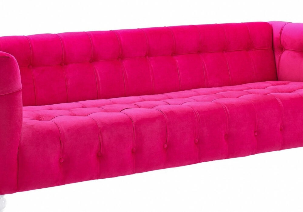 A bright pink, tufted velvet sofa with square arms and clear legs, shown against a white background.